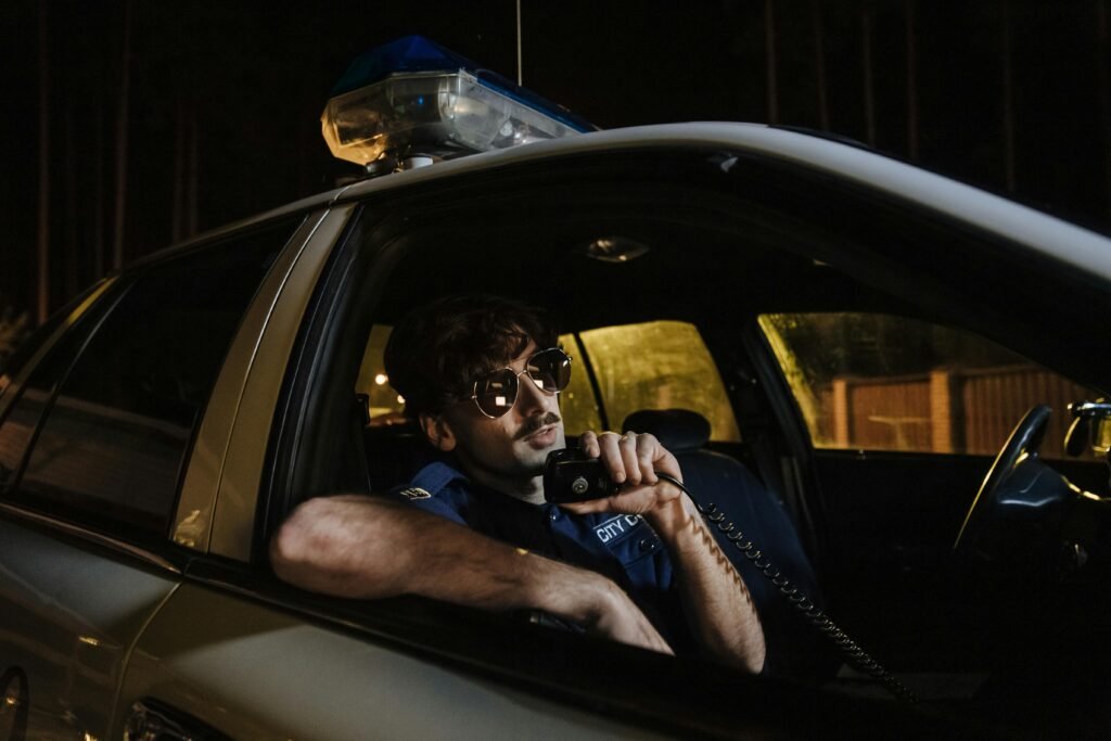 Policeman uses a radio in a patrol car at night, highlighting law enforcement duties.