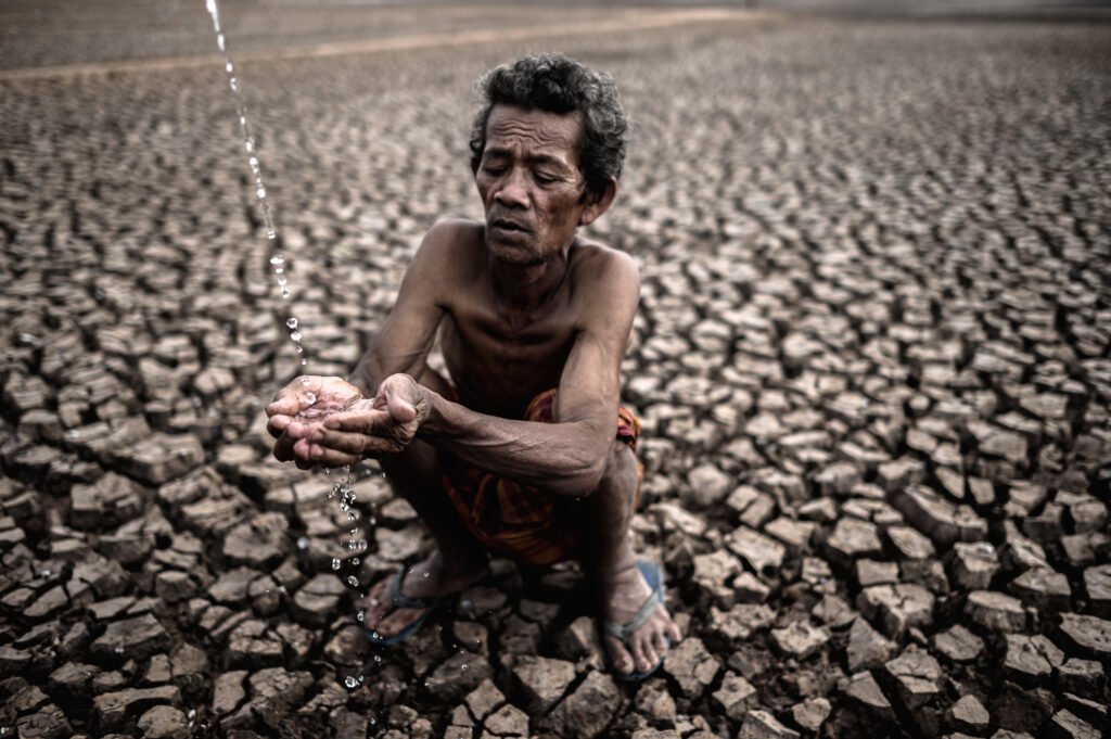 an elderly man sitting in touch with rain in the dry season, glo